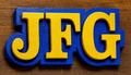 Yellow and blue letters 'JFG' on a wooden background