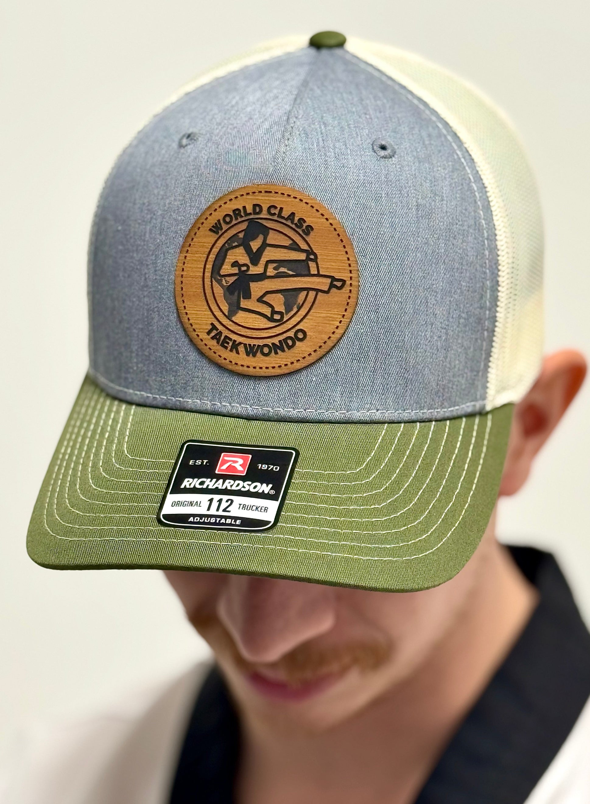 Gray and green baseball cap with leather patch and Richardson logo on a neutral background