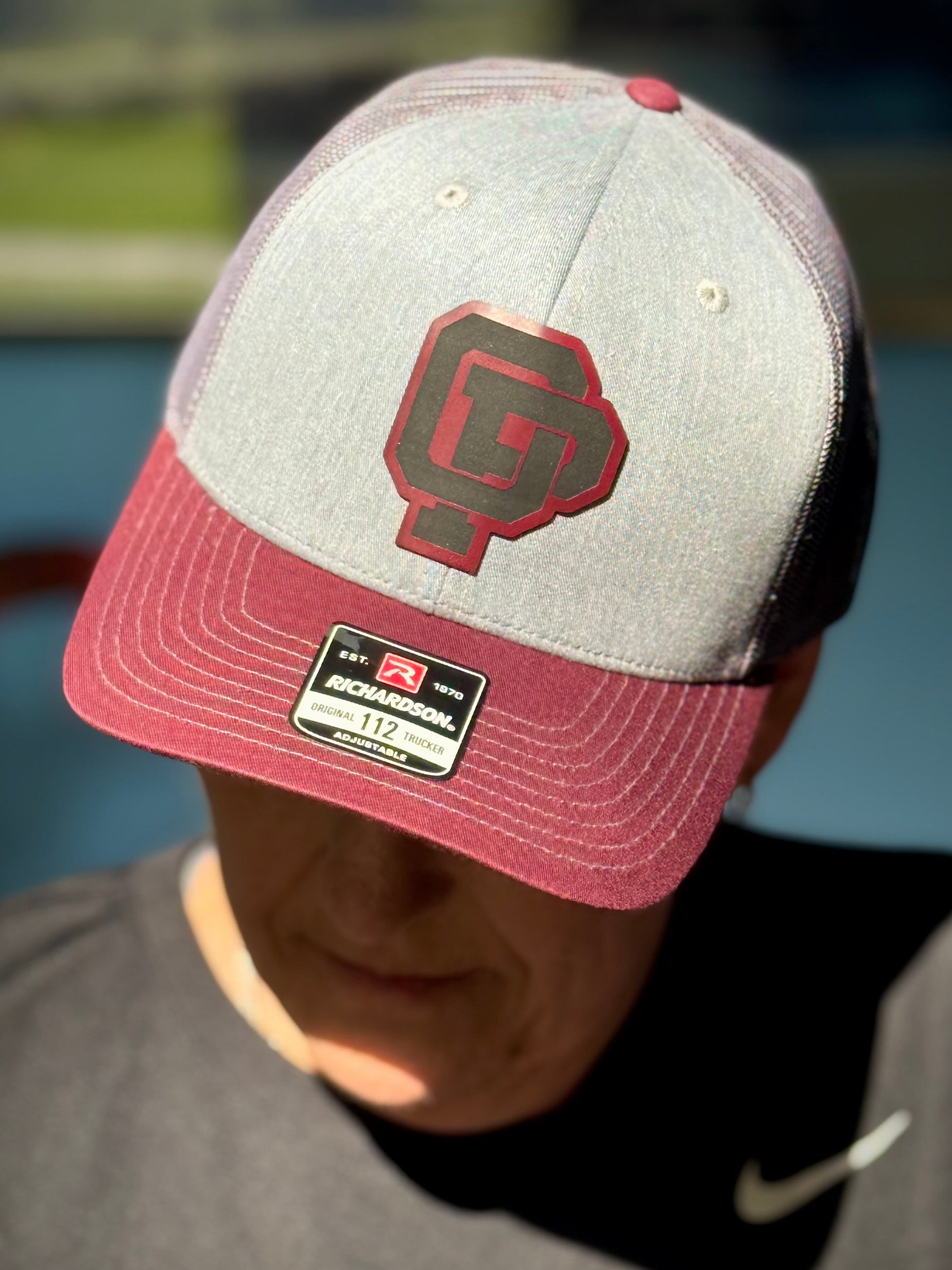 Person wearing a gray and red cap with a logo, outdoors.